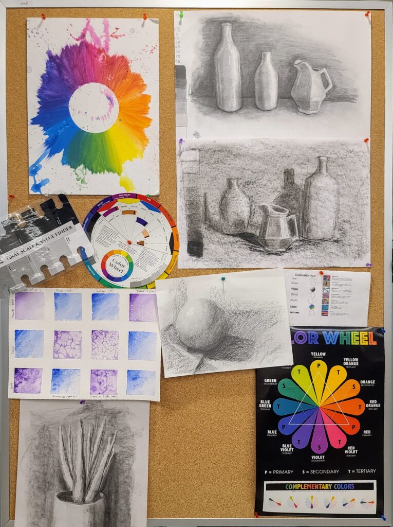 Corkboard display in the library art classroom showing student art studies—charcoal still lifes, color wheels, grayscale value finder, and watercolor salt texture experiments.