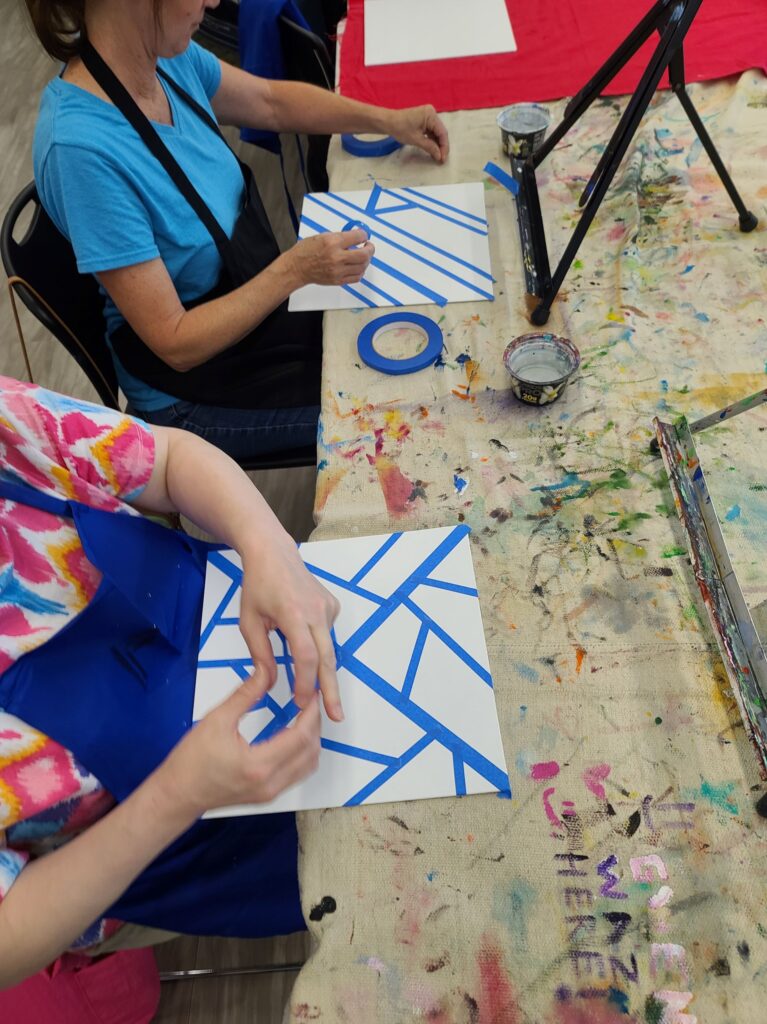 Participants in a workshop prep canvasses with tape.