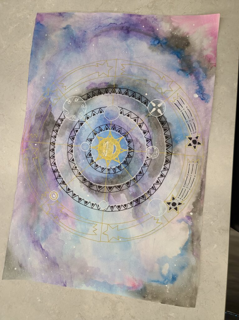 Hands holding a large watercolor mandala featuring a golden sun face in the center surrounded by circular celestial symbols on a purple and blue galaxy background.
