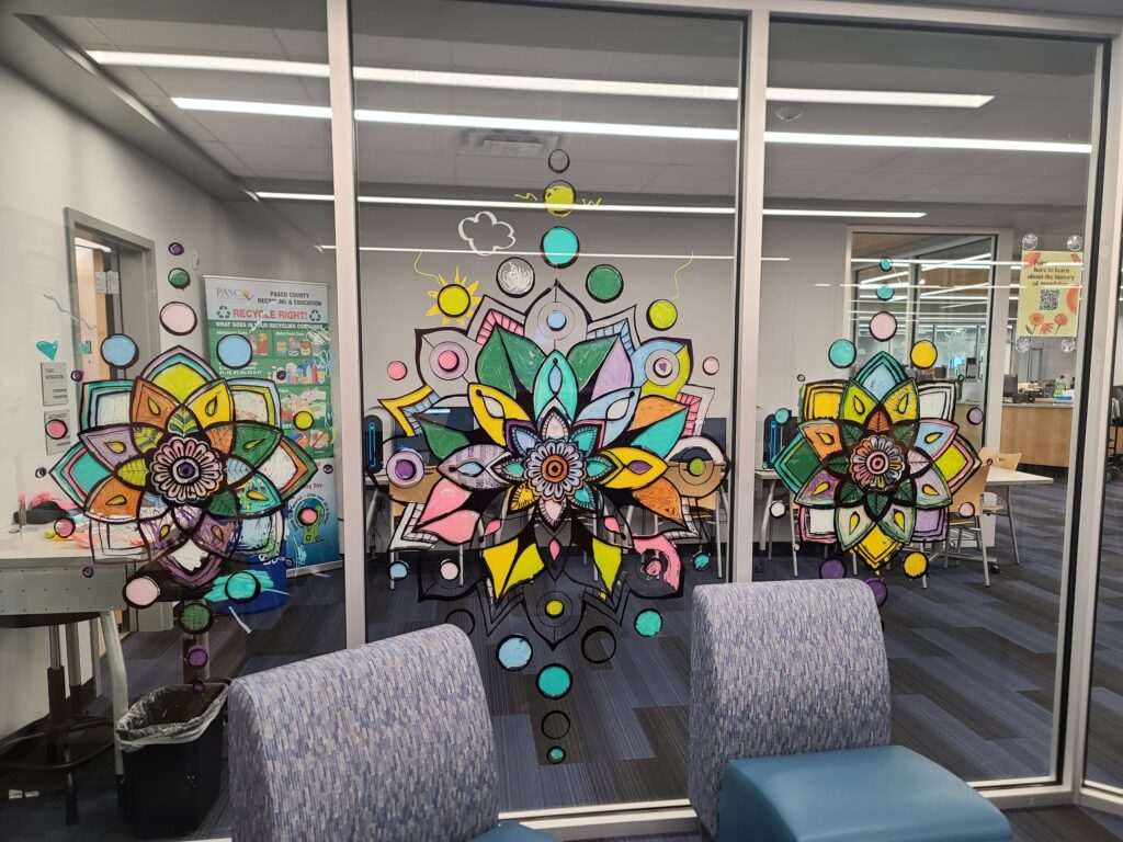 Large colorful mandalas painted on the teen room’s glass wall, created by community participants during an interactive art session.